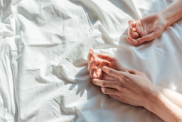 Couple holding hands in bed.png